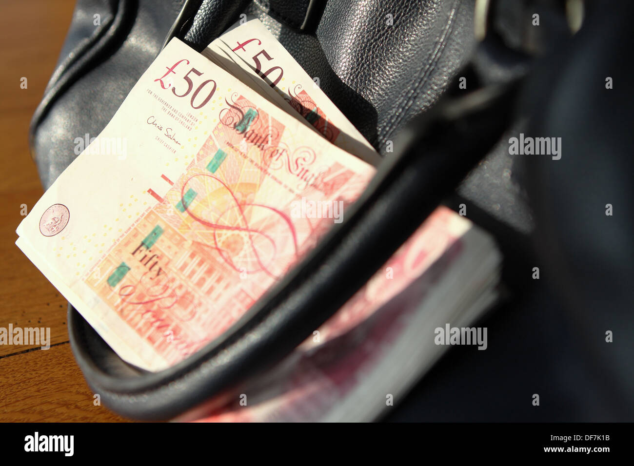 A bunch of sterling £50 notes in between the handle and body of a handbag Stock Photo