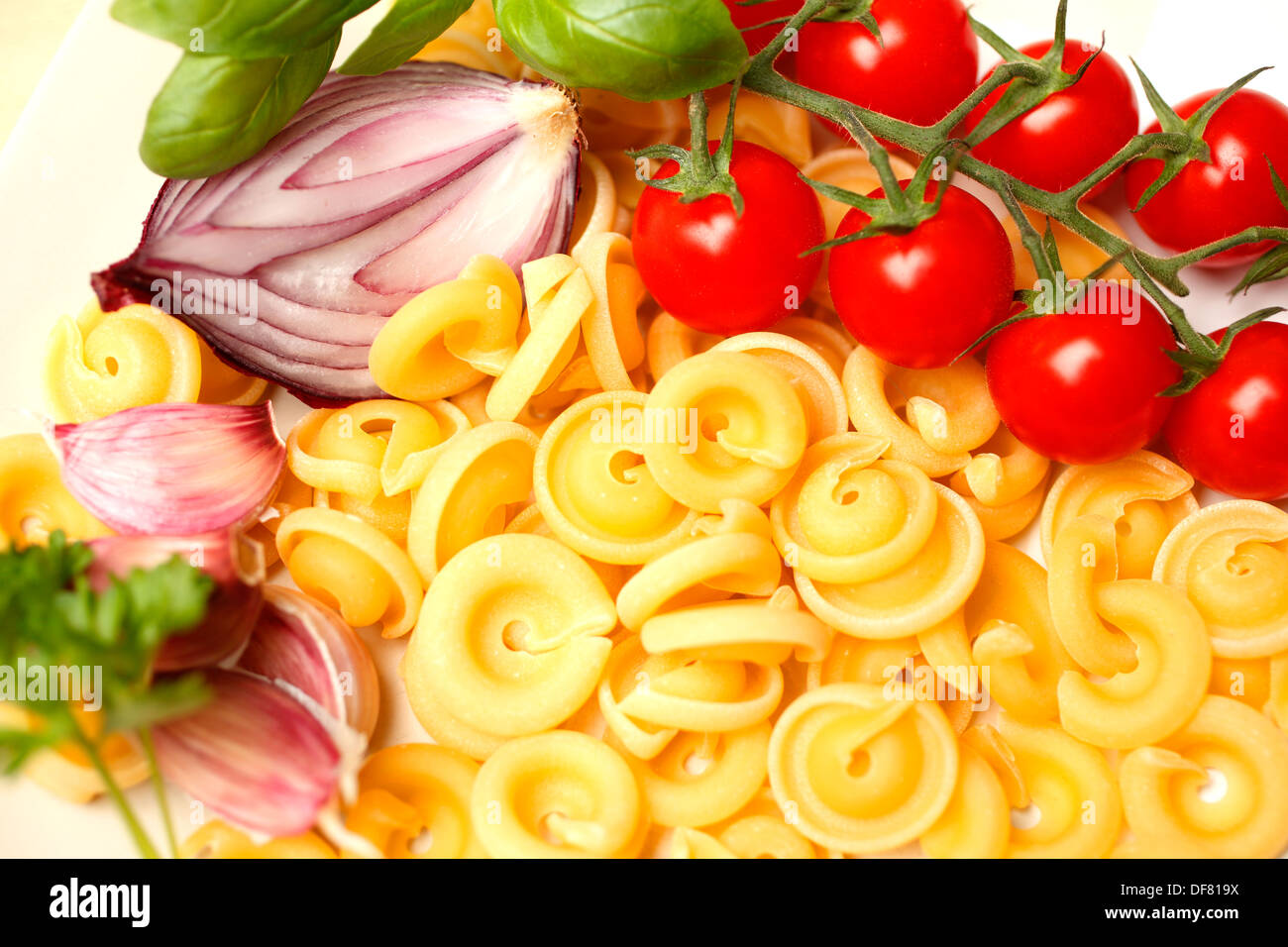 Red Onion, cherry tomatoes, fresh basil, garlic and dischi volanti pasta Stock Photo
