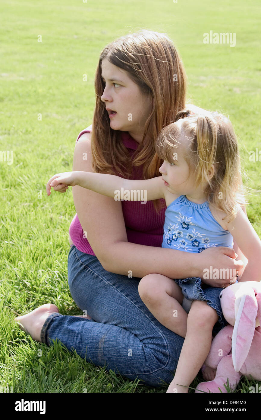 Young daughter sitting on her mother´s lap at the park Stock Photo