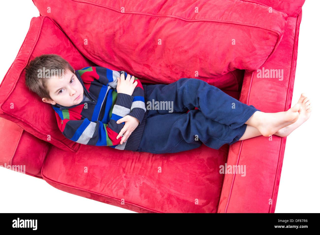 Eight years old boy expression mischievousness with arms closed on the couch by looking up in to your eyes, isolated on white Stock Photo