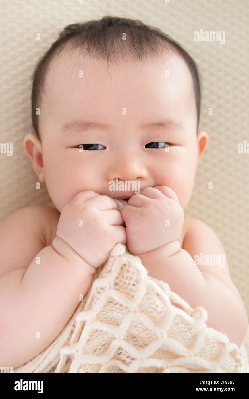 Adorable six months old teething Asian baby girl lying on bed biting blanket Stock Photo Alamy