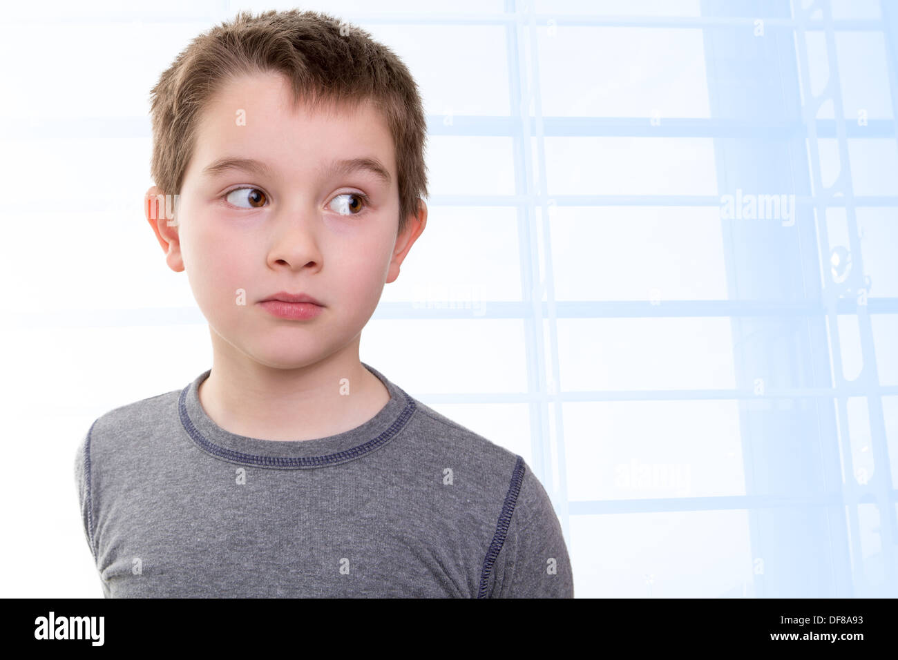 Eight years old kid looking out skeptically accusing with his big eyes Stock Photo