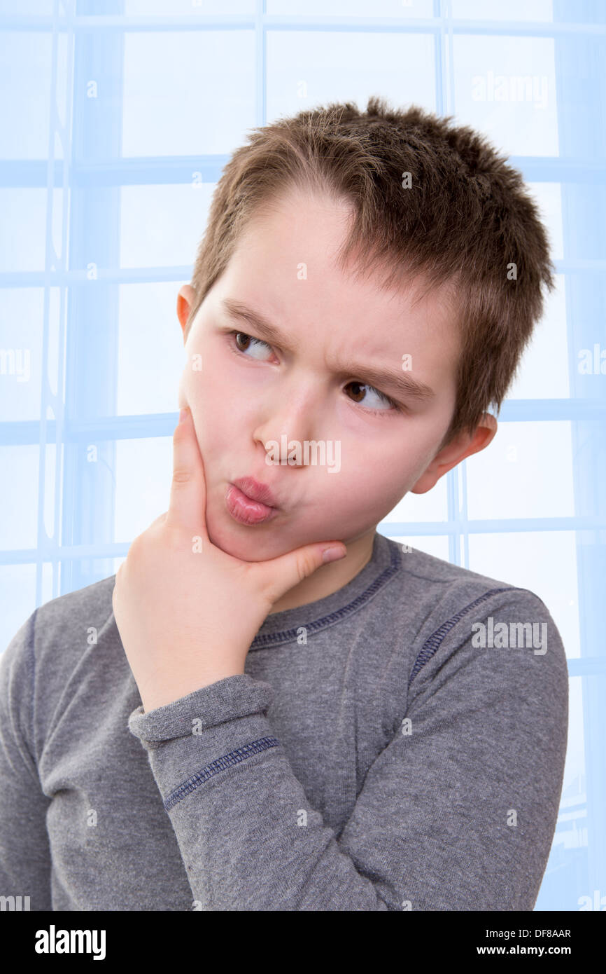 Kid looking away very doubtfully or there might be a math problem he thinks about Stock Photo