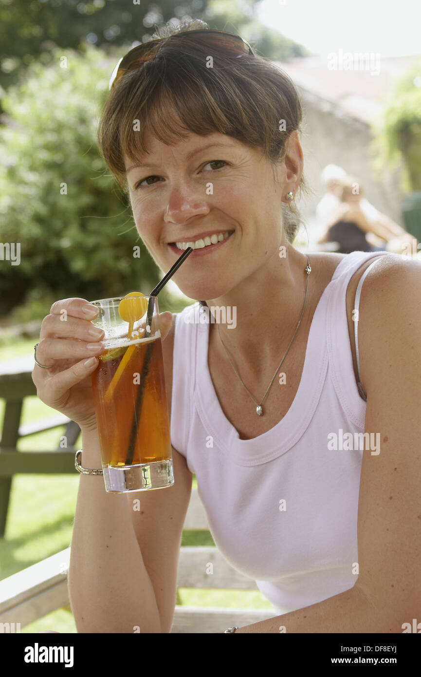 36-year-old-woman-sitting-outside-in-the-sunshine-drinking-a-glass-of