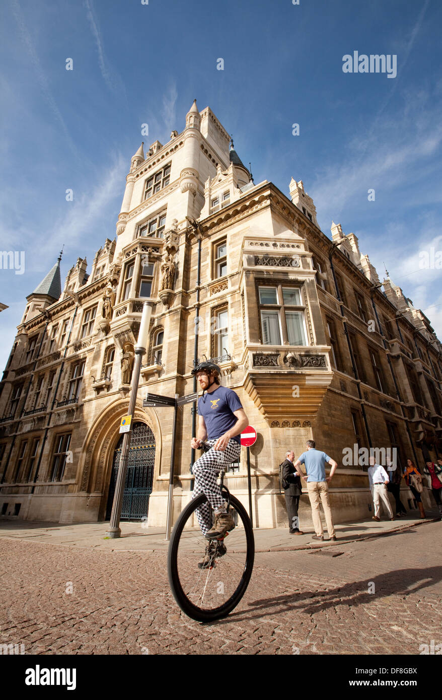 A cambridge student cycling to lectures on a unicycle, outside Gonville & Caius College, Cambridge University, England UK Stock Photo