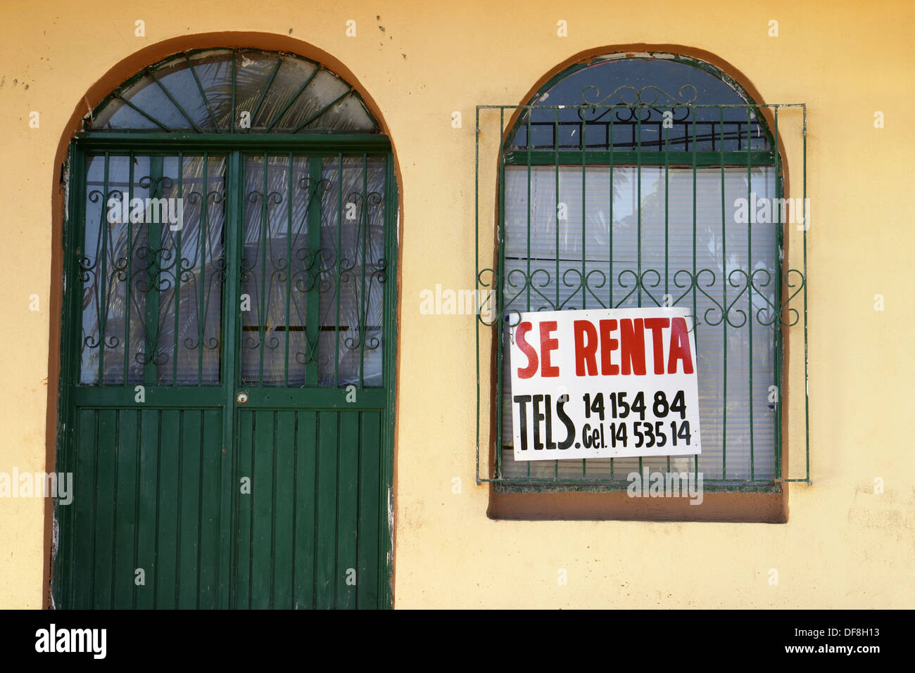 For Rent sign in Spanish, arched door and window with decorative iron