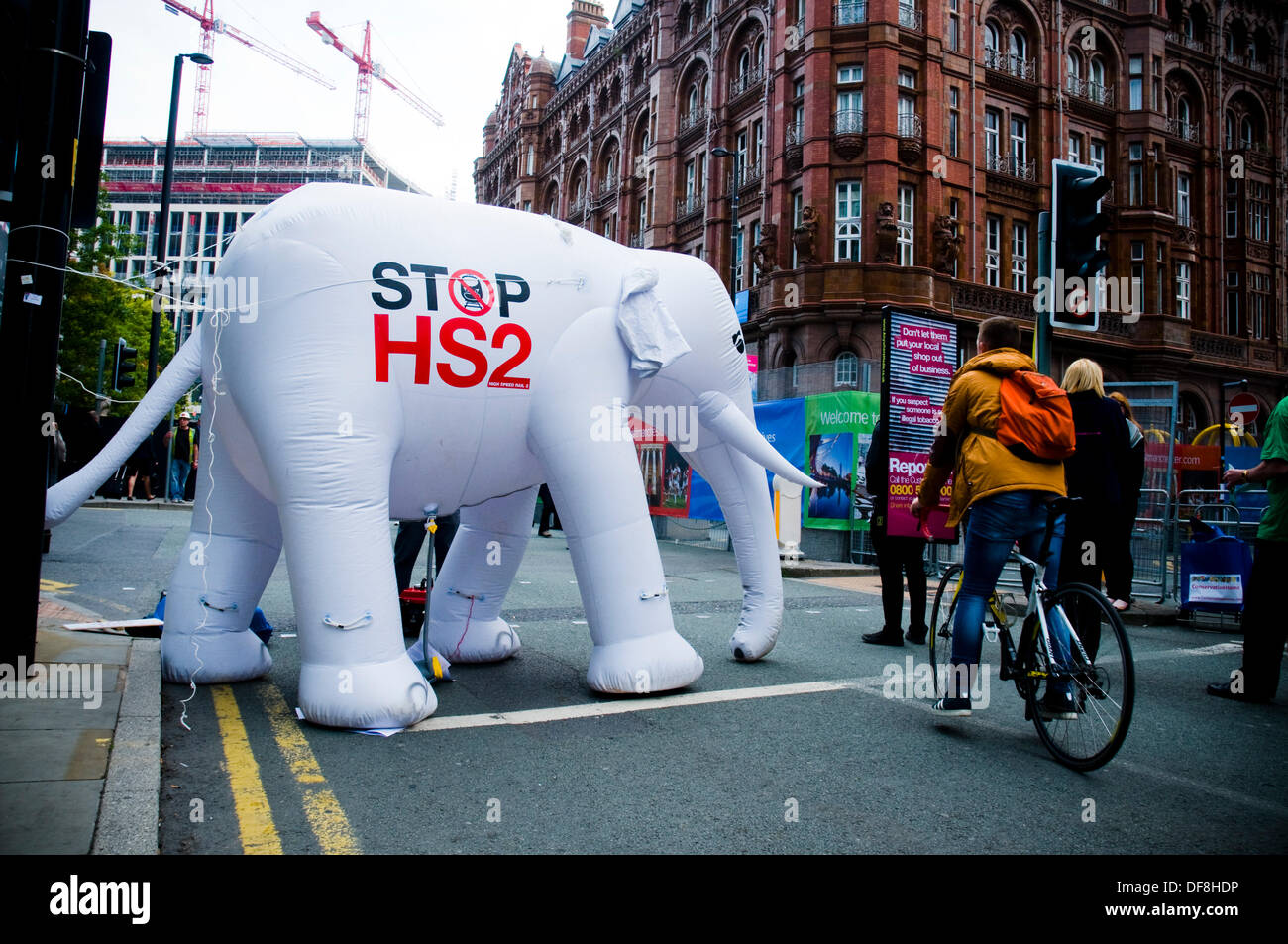 Manchester, UK. 30th Sep, 2013. An inflatable white elephant, campaigning against the building of HS2, blocks the path of a cyclist outside of the Conservative Party Conference. Credit:  Paul Swinney/Alamy Live News Stock Photo