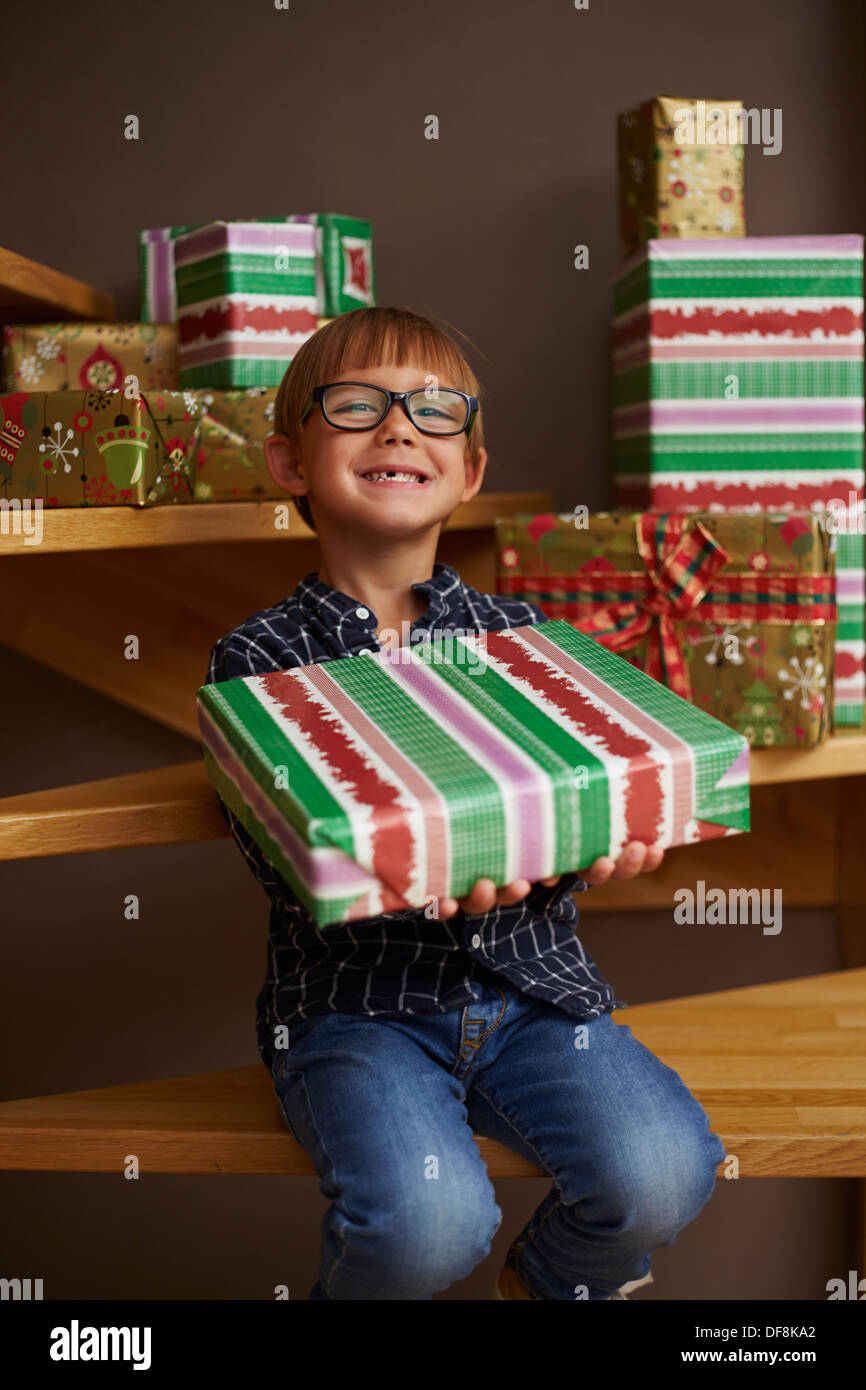 Smiling boy ready to open Christmas presents on the stairs of his house Stock Photo
