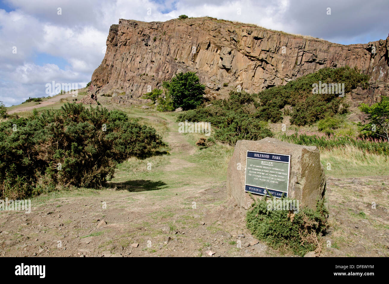 A rough path through Holyrood Park in the centre of Edinburgh heading towards Salisbury Crags in the distance. Stock Photo