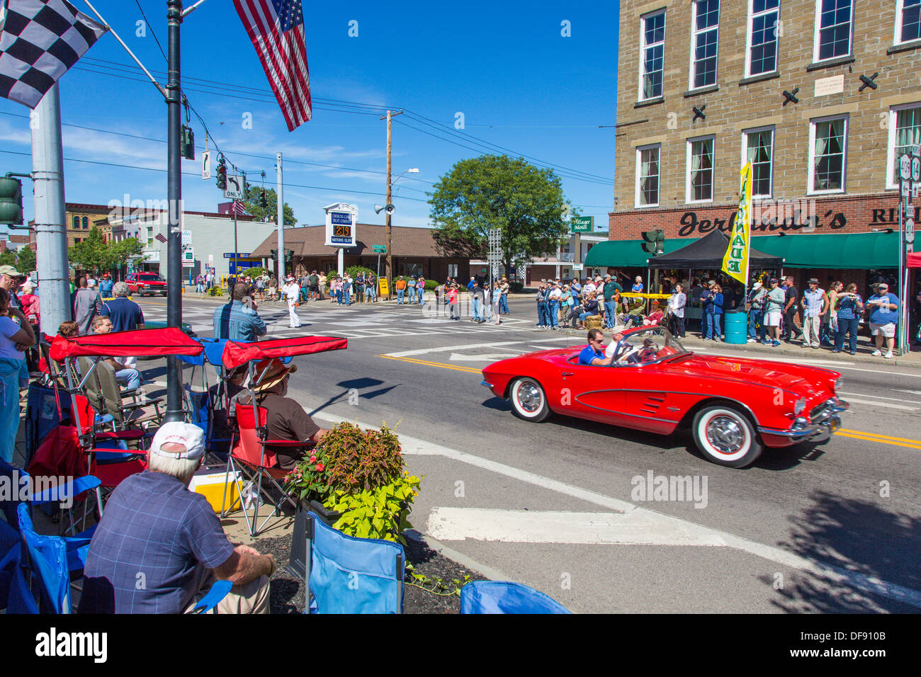 Vintage race cars driving though downtown Watkins Glen during the annual Vintage Race weekend Festival with spectators  watching Stock Photo