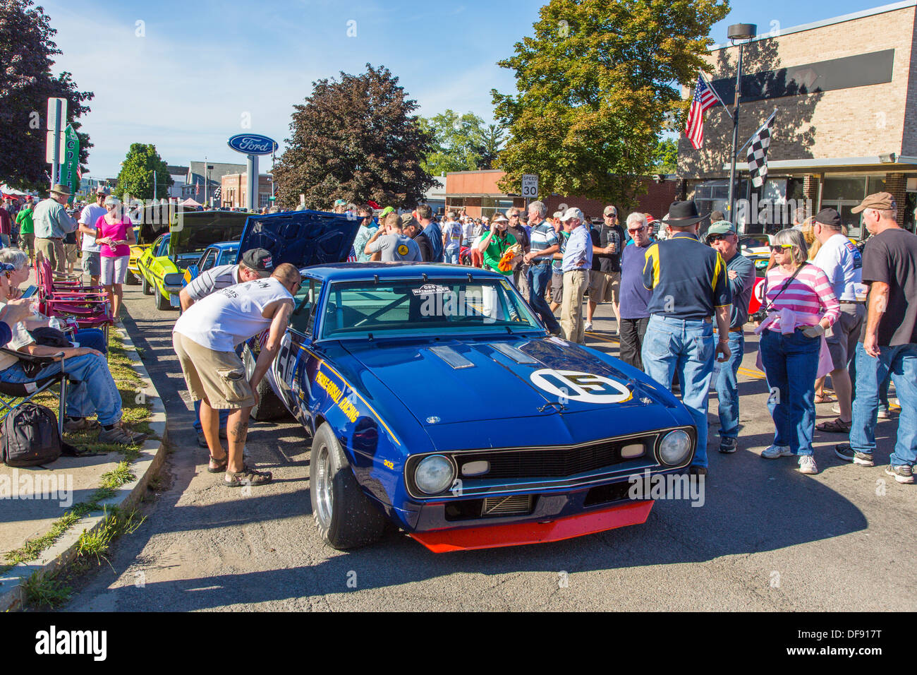 Vintage race cars parked in downtown Watkins Glen during the annual Vintage Race weekend Festival with spectators viewing cars Stock Photo