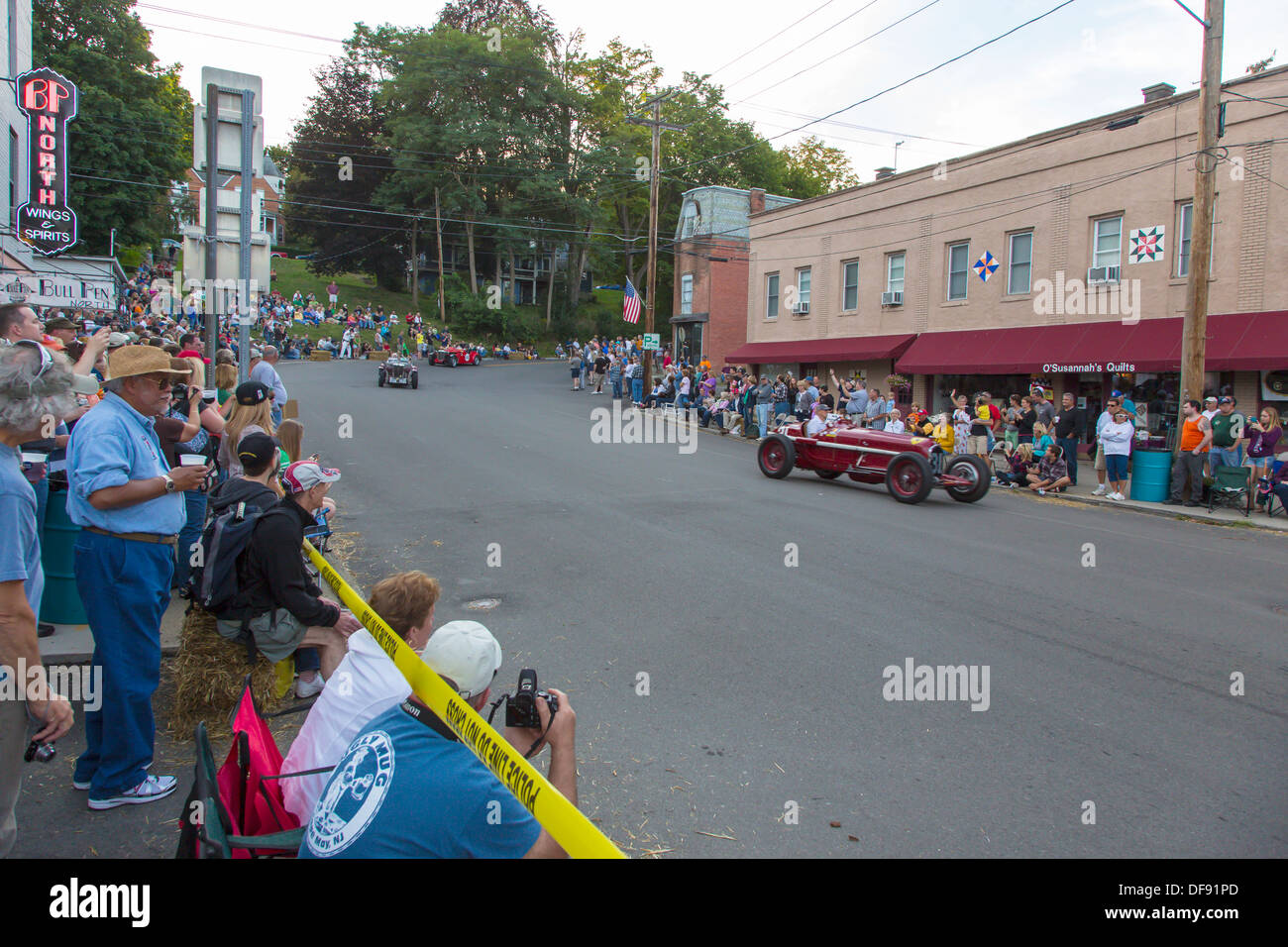 Vintage race cars driving though downtown Watkins Glen during the annual Vintage Race weekend Festival with spectators  watching Stock Photo