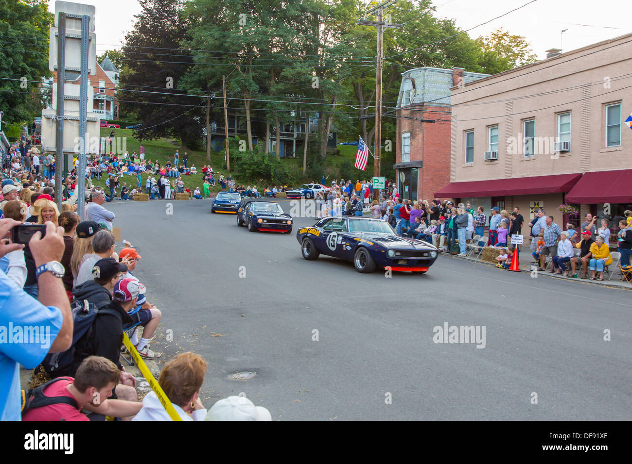Vintage race cars driving though downtown Watkins Glen during the annual Vintage Race weekend Festival with spectators  watching Stock Photo
