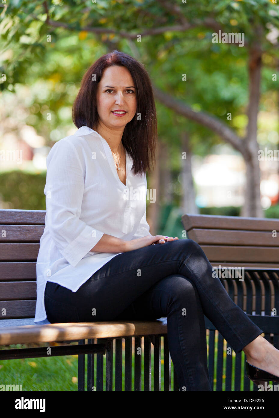 Portrait of woman sitting on park bench Stock Photo - Alamy