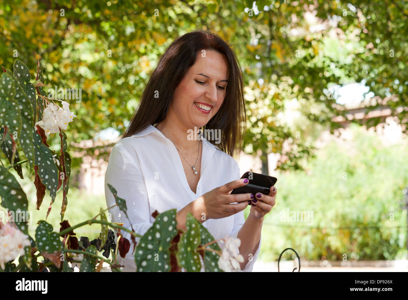 Middle aged Caucasian woman using smart phone in garden Stock Photo
