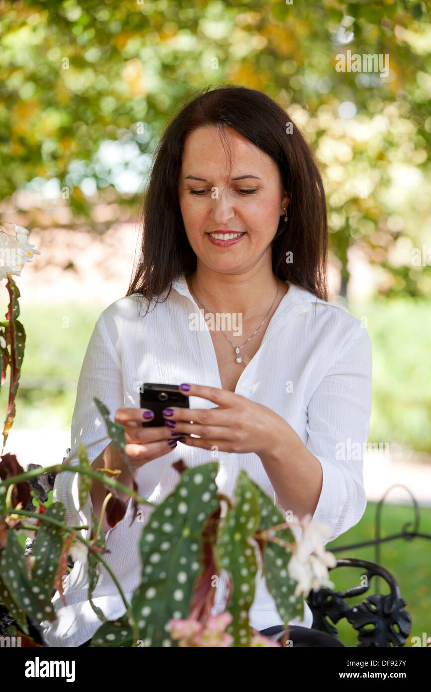 Middle aged Caucasian woman using smart phone in garden Stock Photo