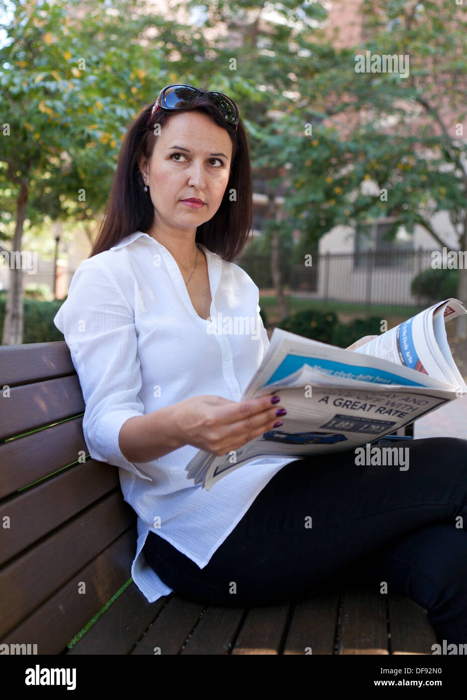 Woman reading newspaper outdoor bench Stock Photo