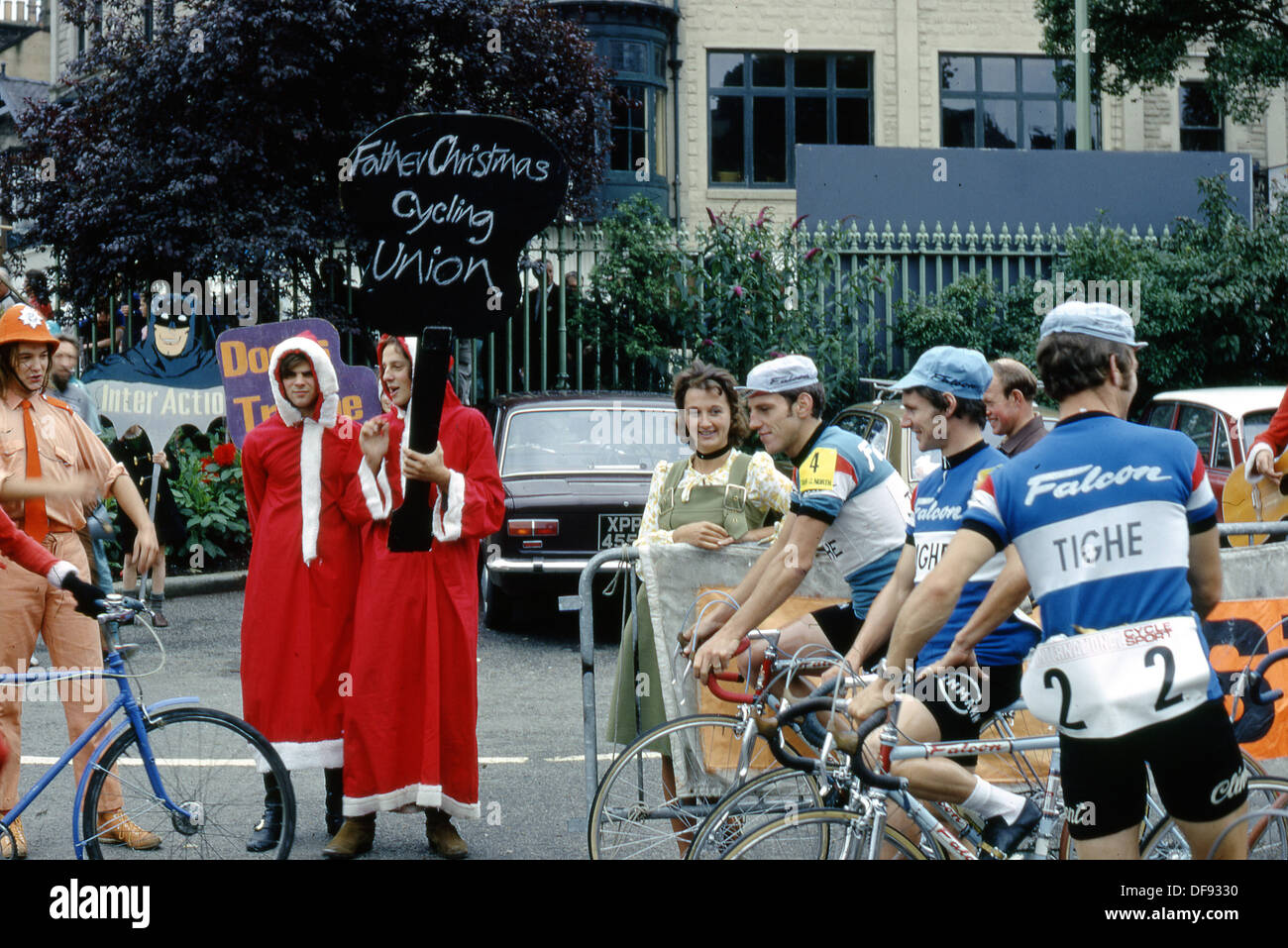 1970s, picture of spectators at the start of a road cycling event, two of who are dressed in red robes as santa claus, one holding a banner saying 'Father Christmas Cycling Union'. Stock Photo