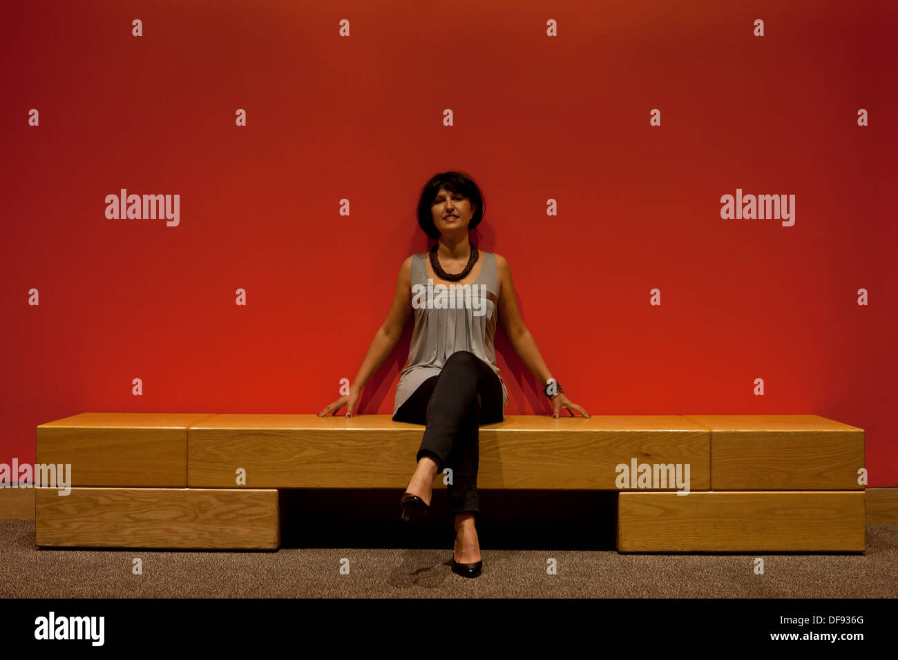 Woman sitting against a red wall Stock Photo
