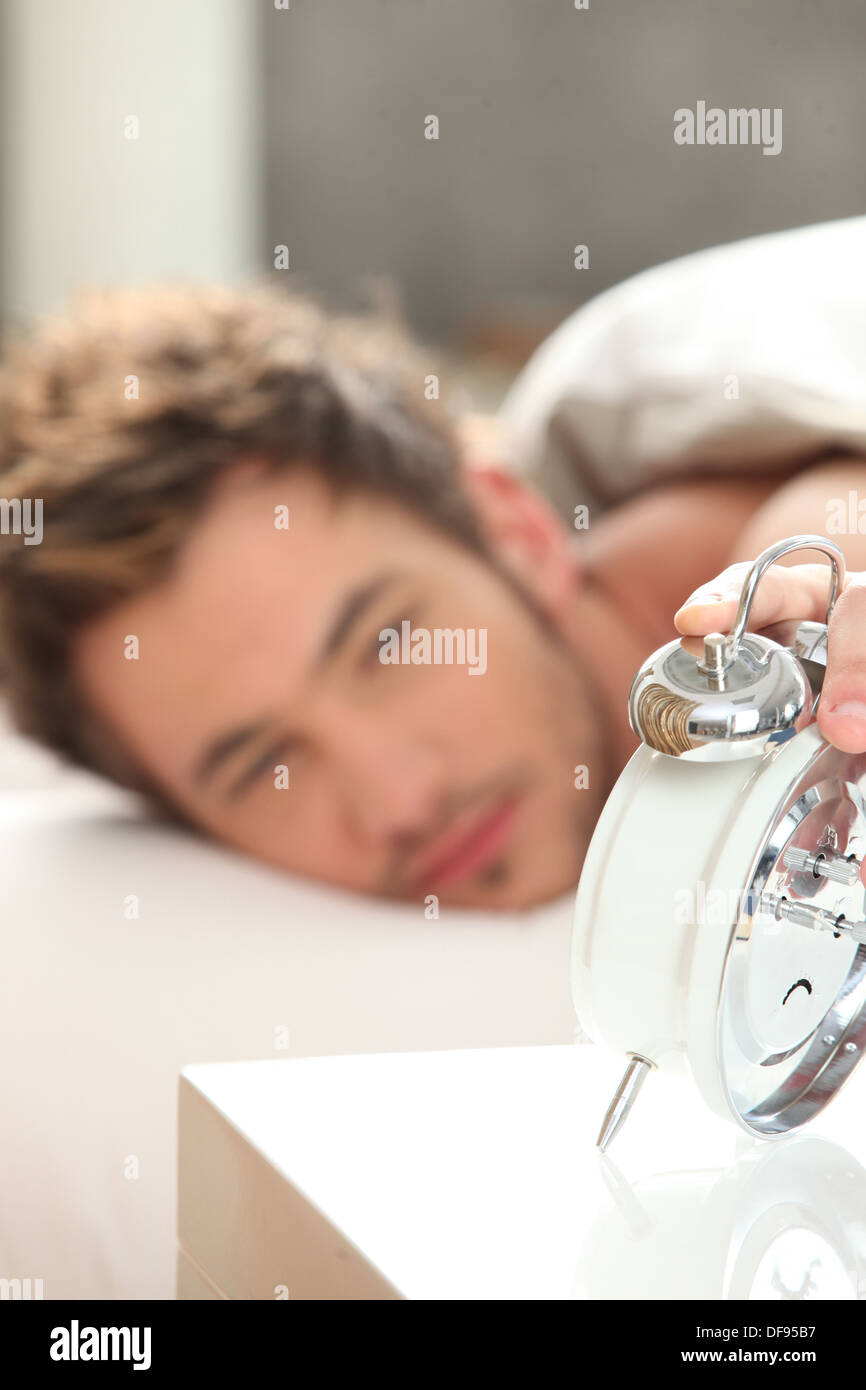 Man looking at his alarm clock Stock Photo - Alamy
