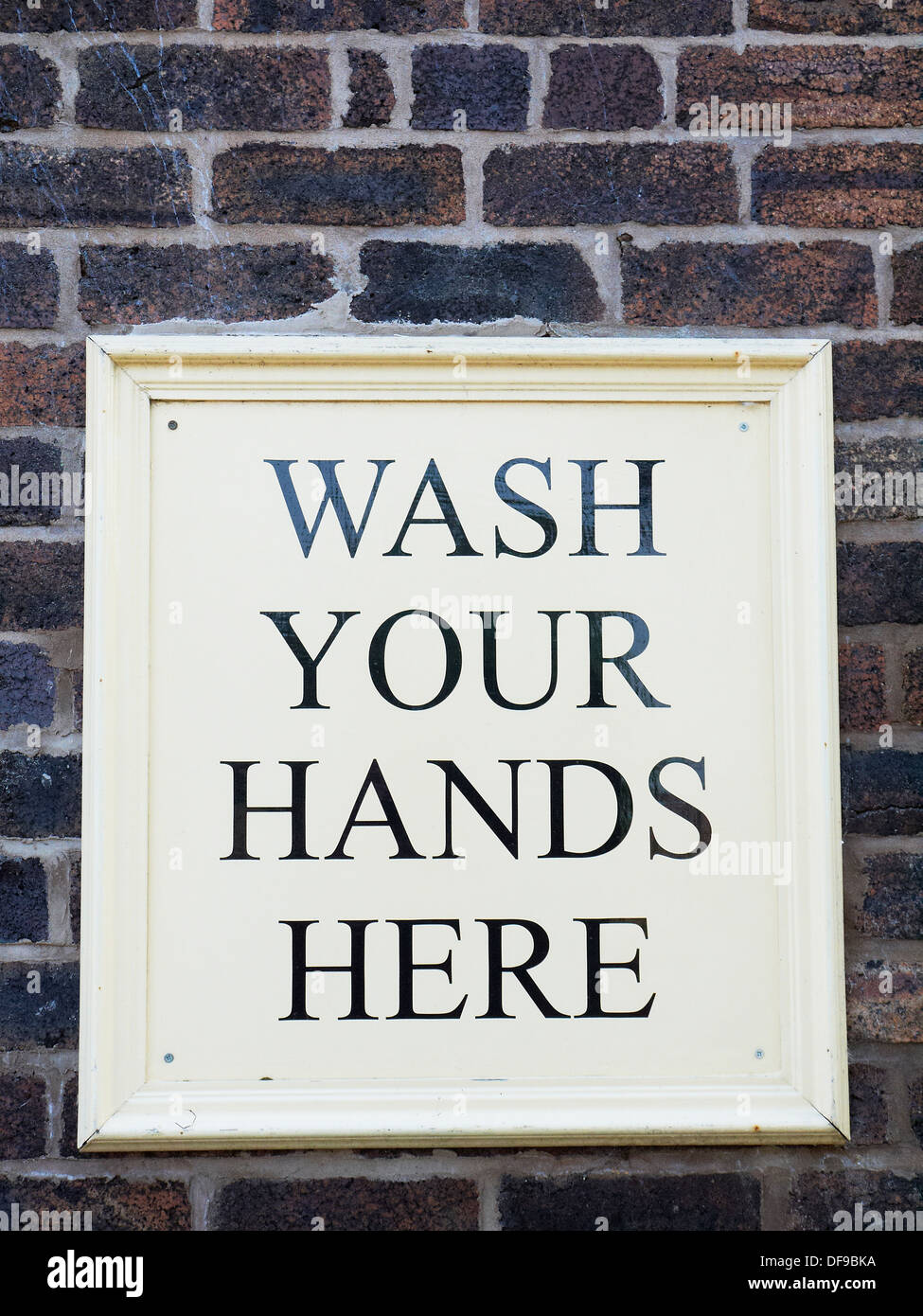 Wash your hands here sign on outside wall UK Stock Photo