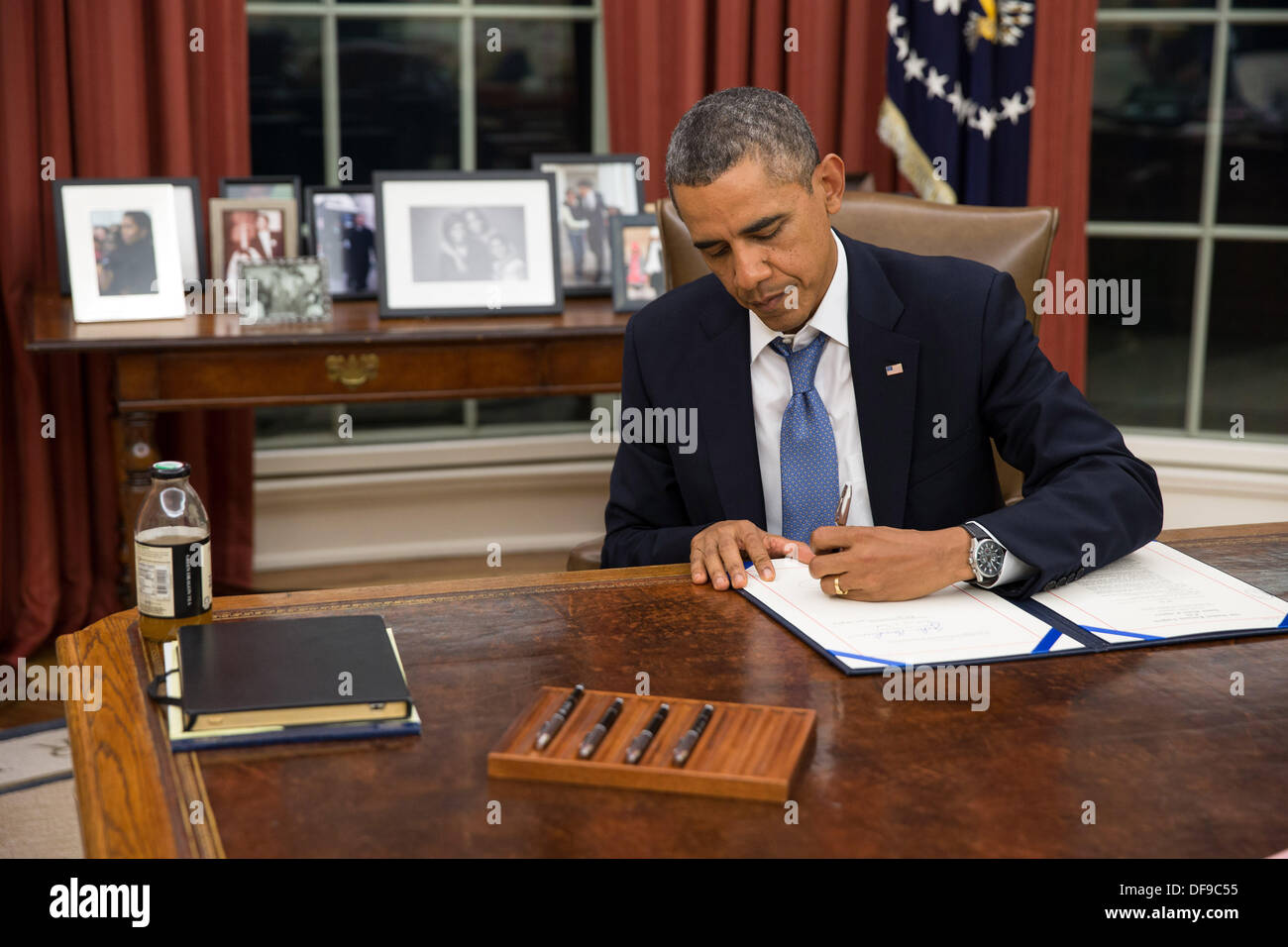 US President Barack Obama signs H.R. 3210, Pay Our Military Act, which provides continuing appropriations for pay and allowances for members of the Armed Forces during any government shutdown in the Oval Office of the White House September 30, 2013 in Washington, DC. Stock Photo