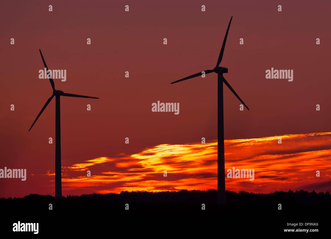 The rotor blades of a set of wind turbines turn in the red early morning glow of the rising sun in Klein Welzin, Germany, 1 October 2013. Photo: Jens Buettner Stock Photo