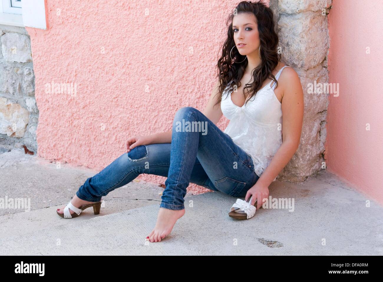 Beautiful Young Woman Is Sitting Next To A Pink Wall With One Foot Bare Beautiful Young Woman Is Sitting Next To A Pink Wall With One Foot Bare