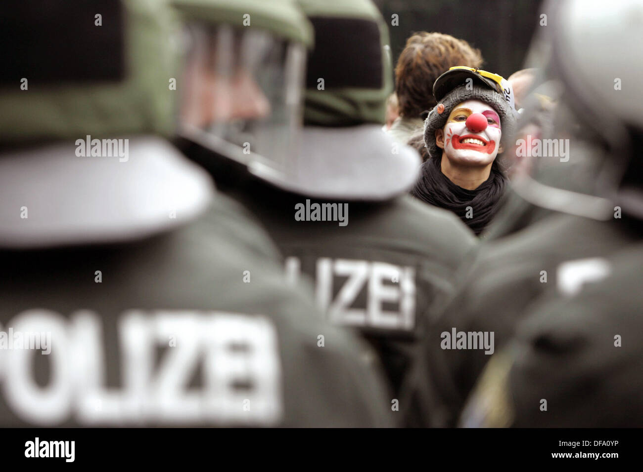 A G8 protester dressed up as a clown peeks through a row of riot police personnel at a rally at on the occasion of 'Migration Day' in Rostock, Germany, 4 June 2007. The G8 summit will take place in Heiligendamm from 06 to 08 of June. Photo: Jan Woitas Stock Photo