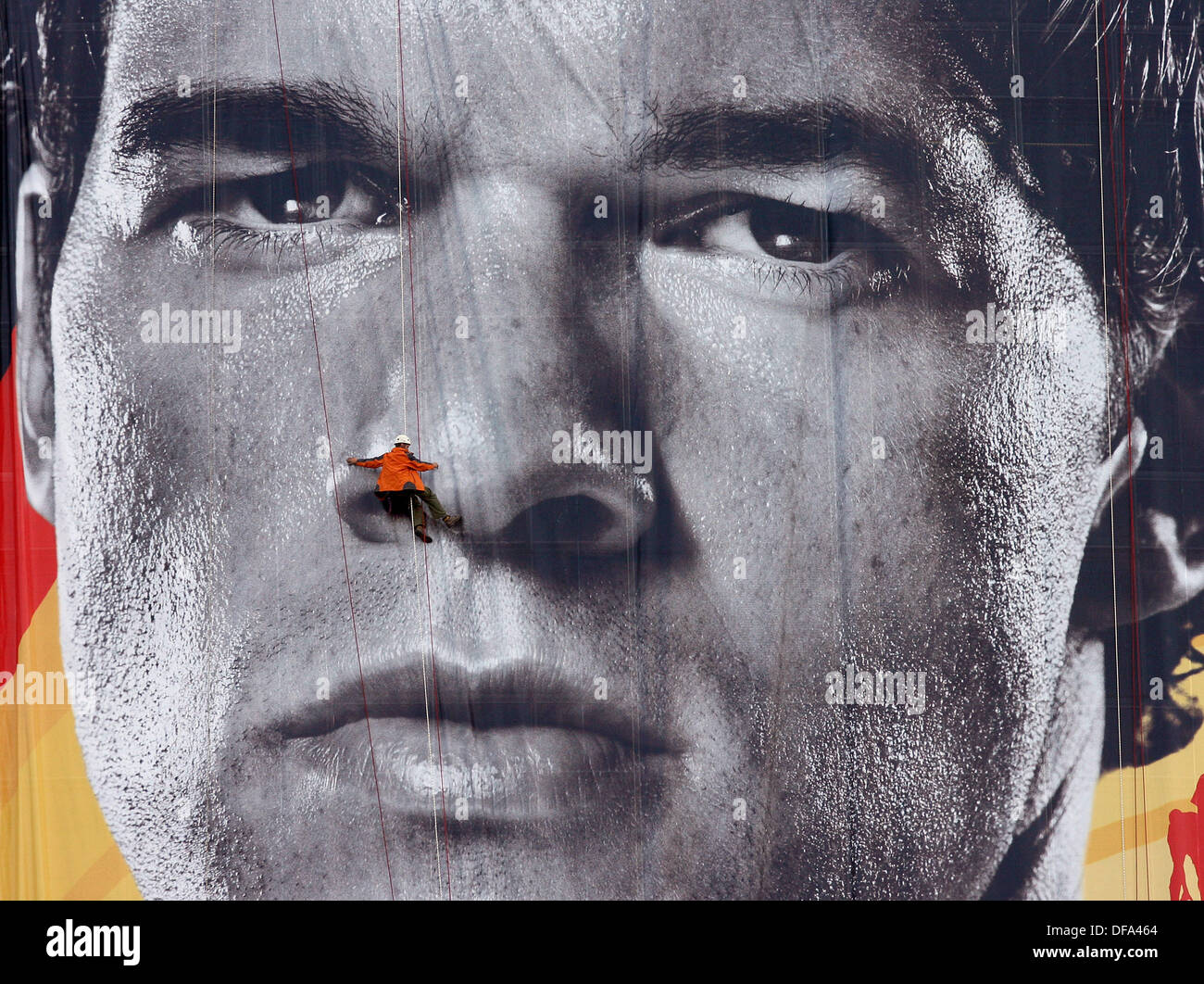 A climber appears like a dwarf as he climbs along an oversized poster of Michael Ballack on the 7th of June in 2006. Stock Photo