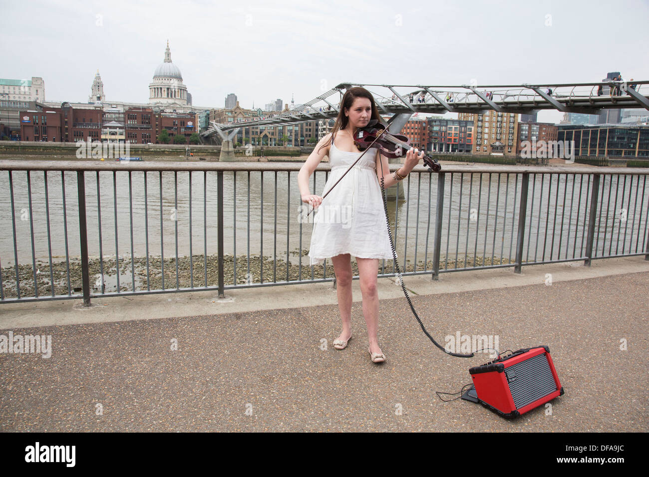 Young busker performing her violin music at Bankside near Millennium Bridge on the Southbank. South Bank is a significant arts and entertainment district, it's riverside walkway busy with visitors and tourists. London, UK. Stock Photo