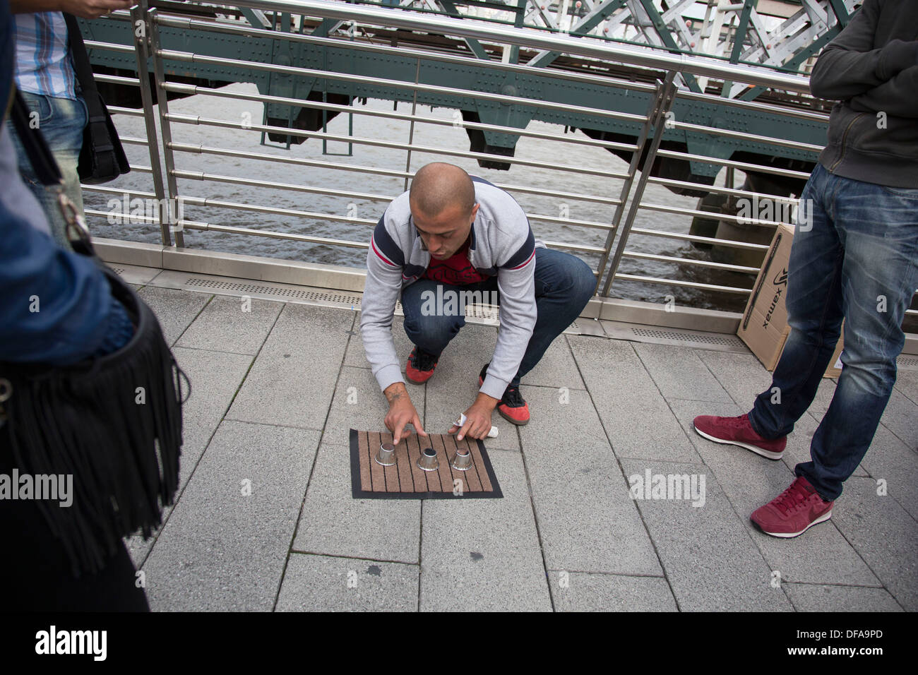 Man playing a con game for passers by. Three-card Monte (aka Find the Lady  or Three card Trick) is a confidence game Stock Photo - Alamy