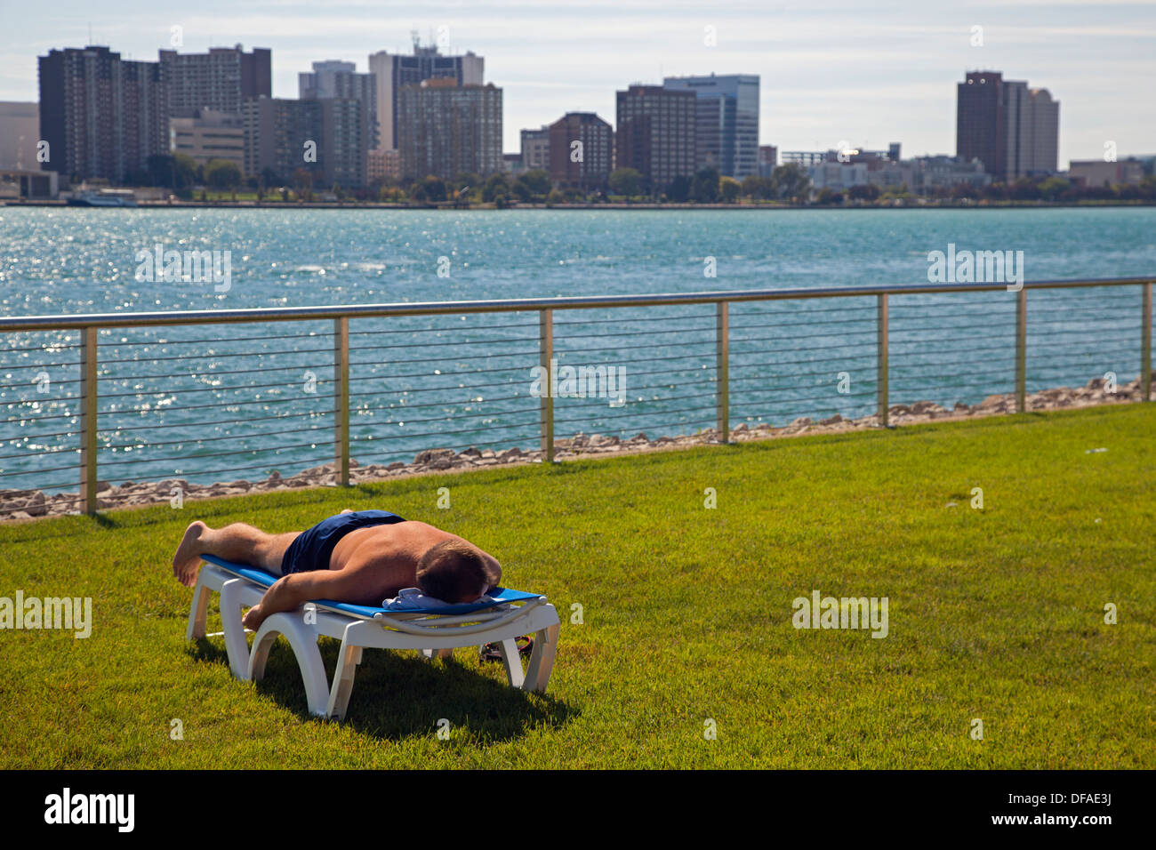 Detroit, Michigan - A man works on his sun tan while lying on a chair near the Detroit River. Stock Photo
