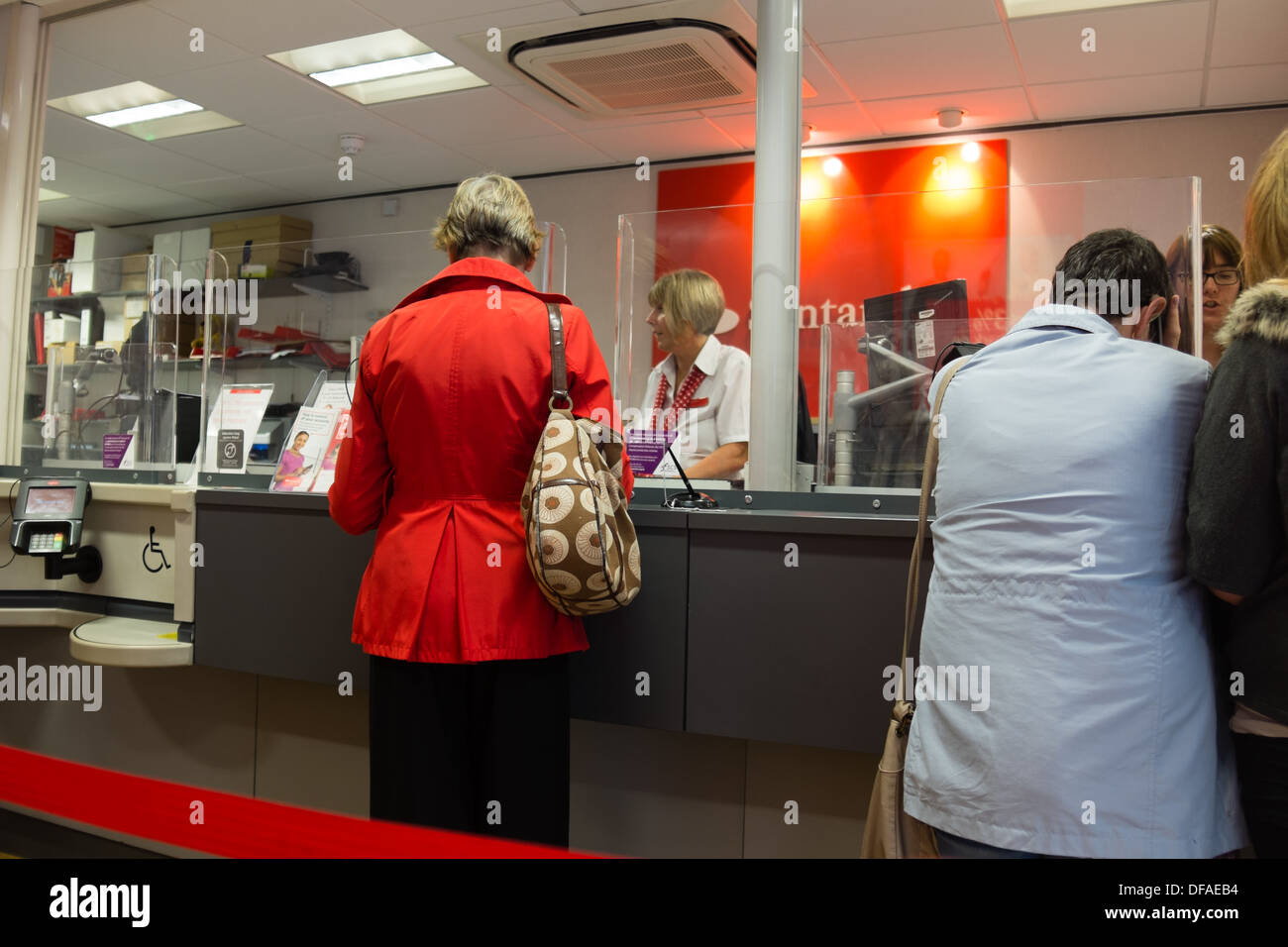 A teller working serving customers at a branch of Santander Bank, UK Stock Photo