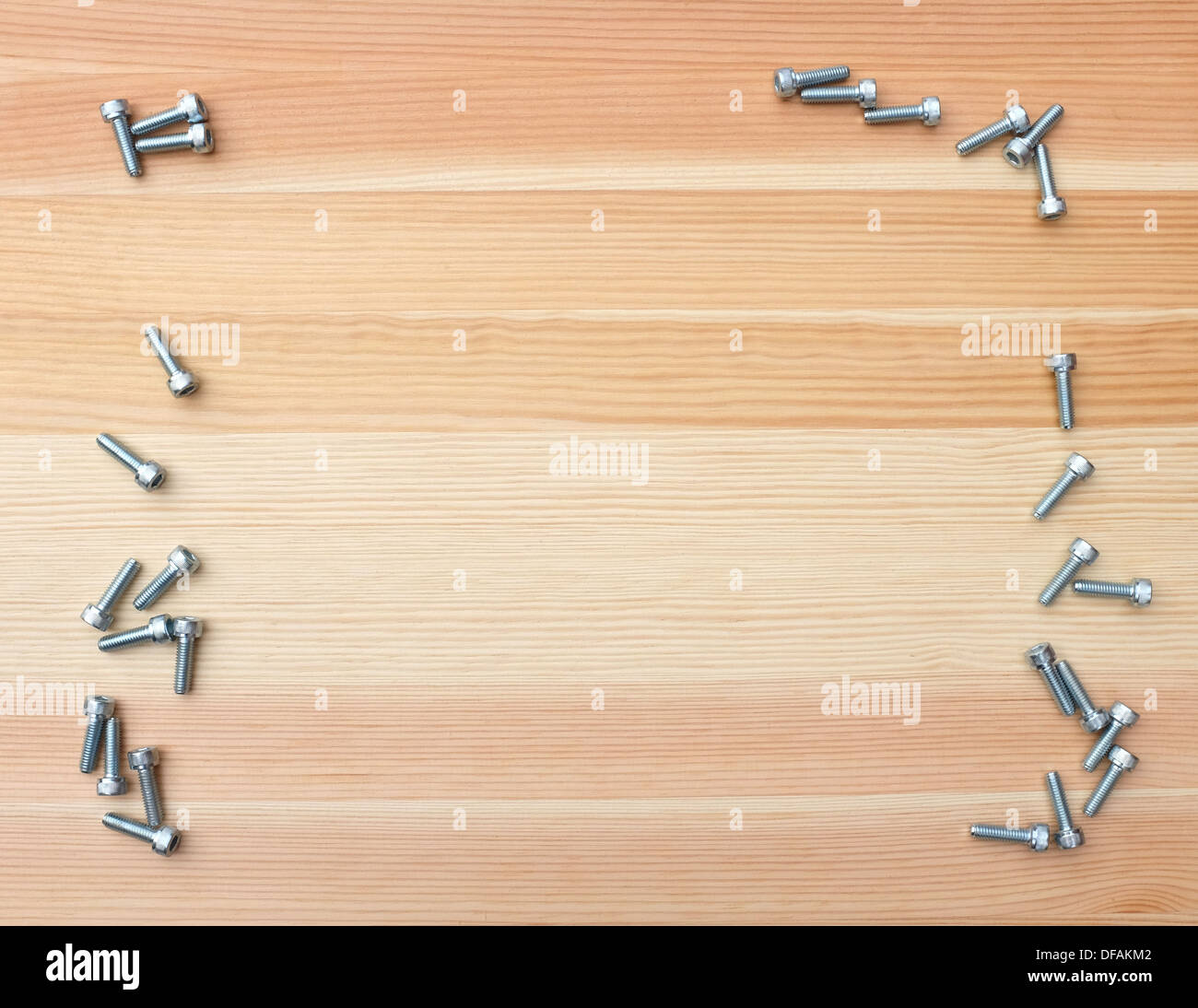 Socket head screws form a rough twosided border on wooden background