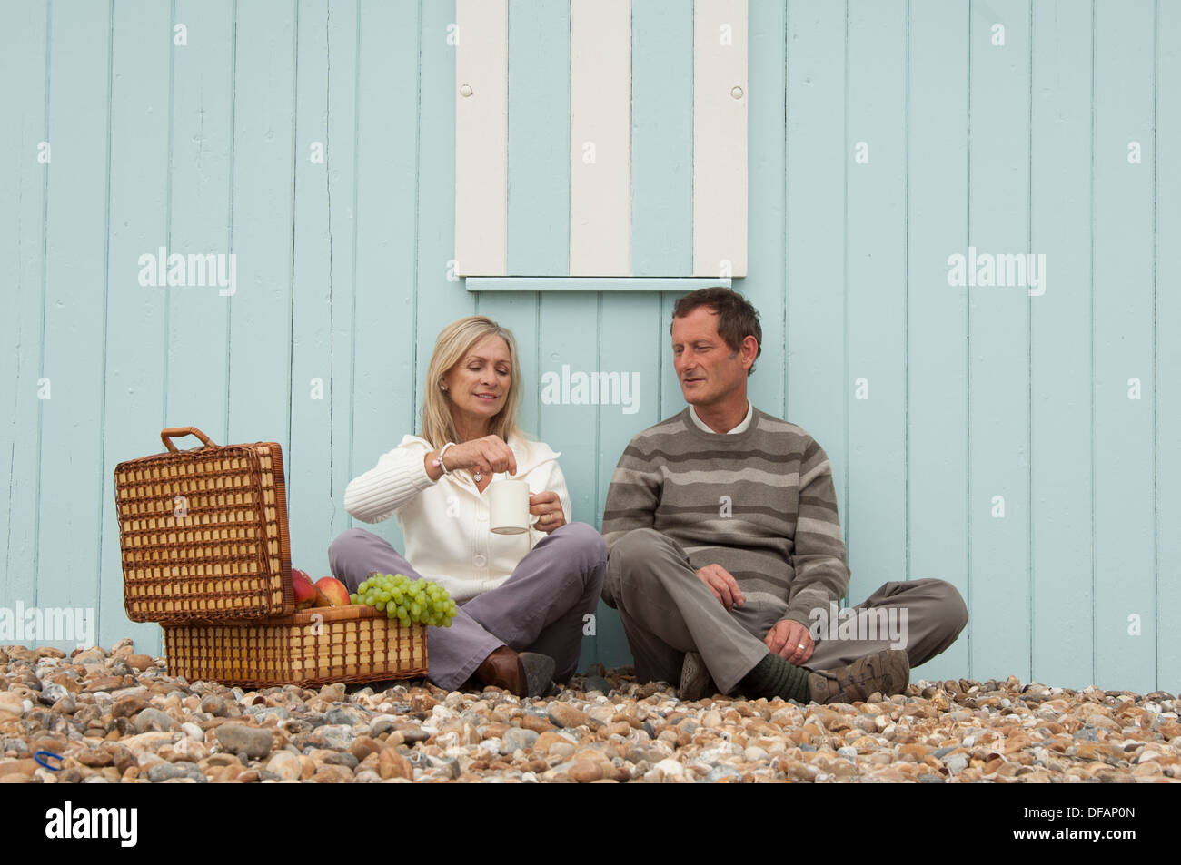 middle aged couple enjoying a picnic on the beach Stock Photo