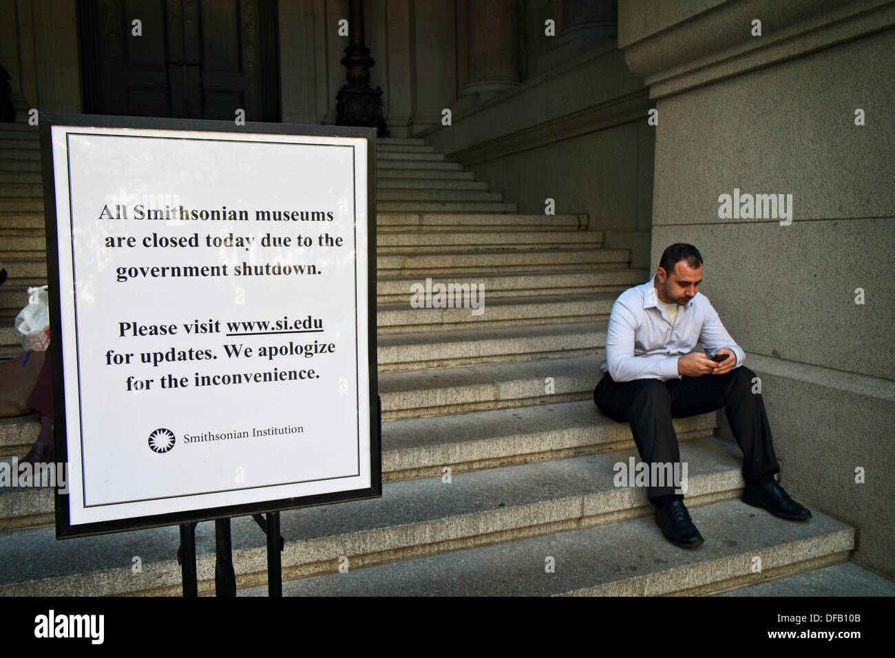 New York, NY, US, October 1, 2013; Man sits on steps of National Museum of the American Indian next to sign noting closure of all Smithsonian museums due to the partial federal government shutdown. Credit:  Joseph Reid/Alamy Live News Stock Photo