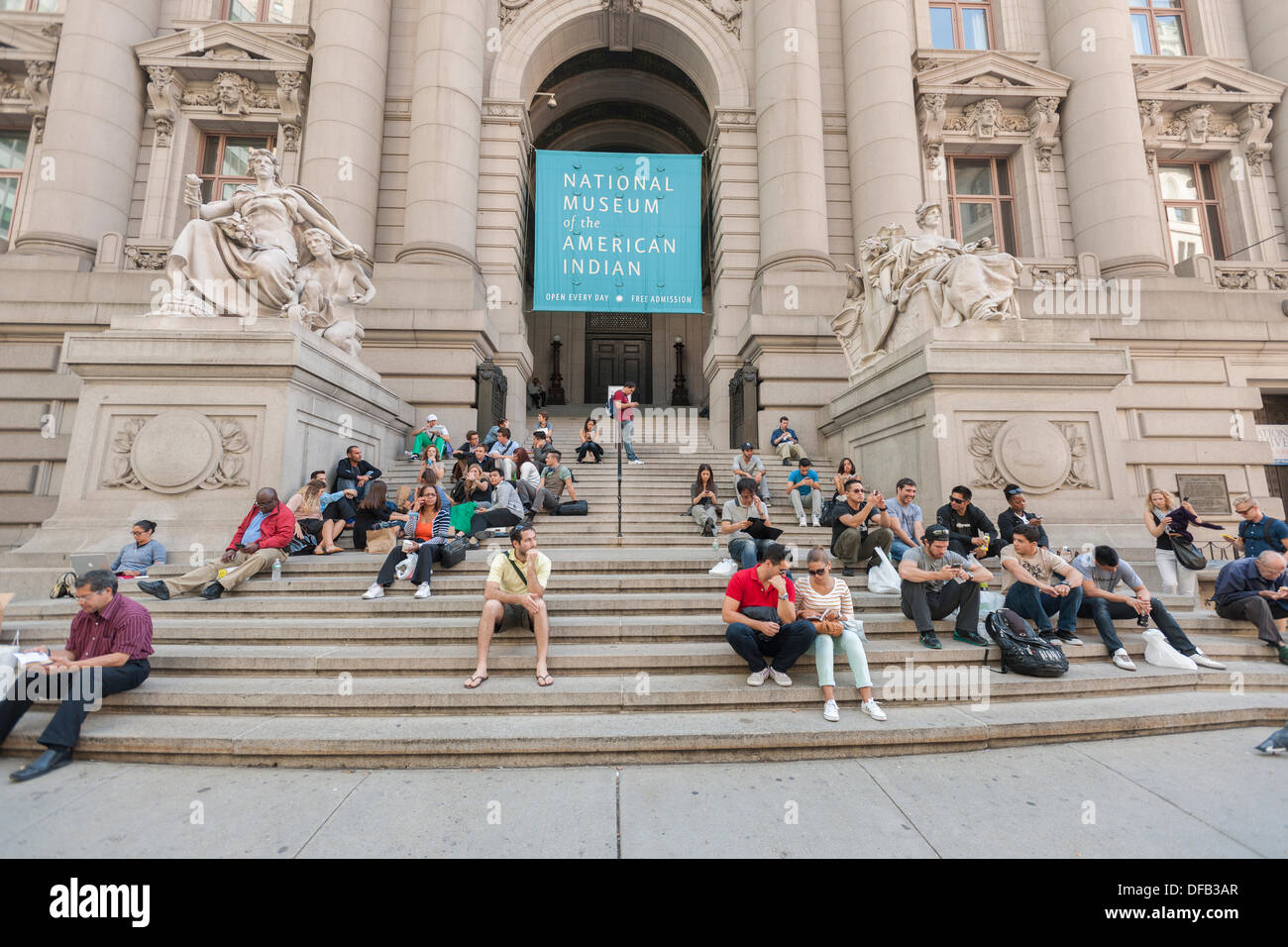 New York, USA. 1st October 2013. Tourists sit on the steps of the closed Smithsonian National Museum of the American Indian in Bowling Green in New York on Tuesday, October 1, 2013. A partial government shutdown took effect today because of a dispute between Democrats and Republicans in Congress over the Obamacare program. Approximately 800,000 federal workers have been furloughed and only essential services are up and running.  Credit:  Richard B. Levine/Alamy Live News Stock Photo