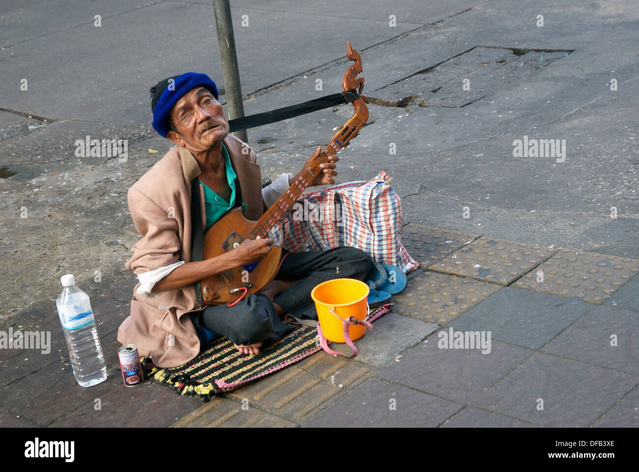Poor beggar with severe facial injury plays guitar Asian Stock Photo