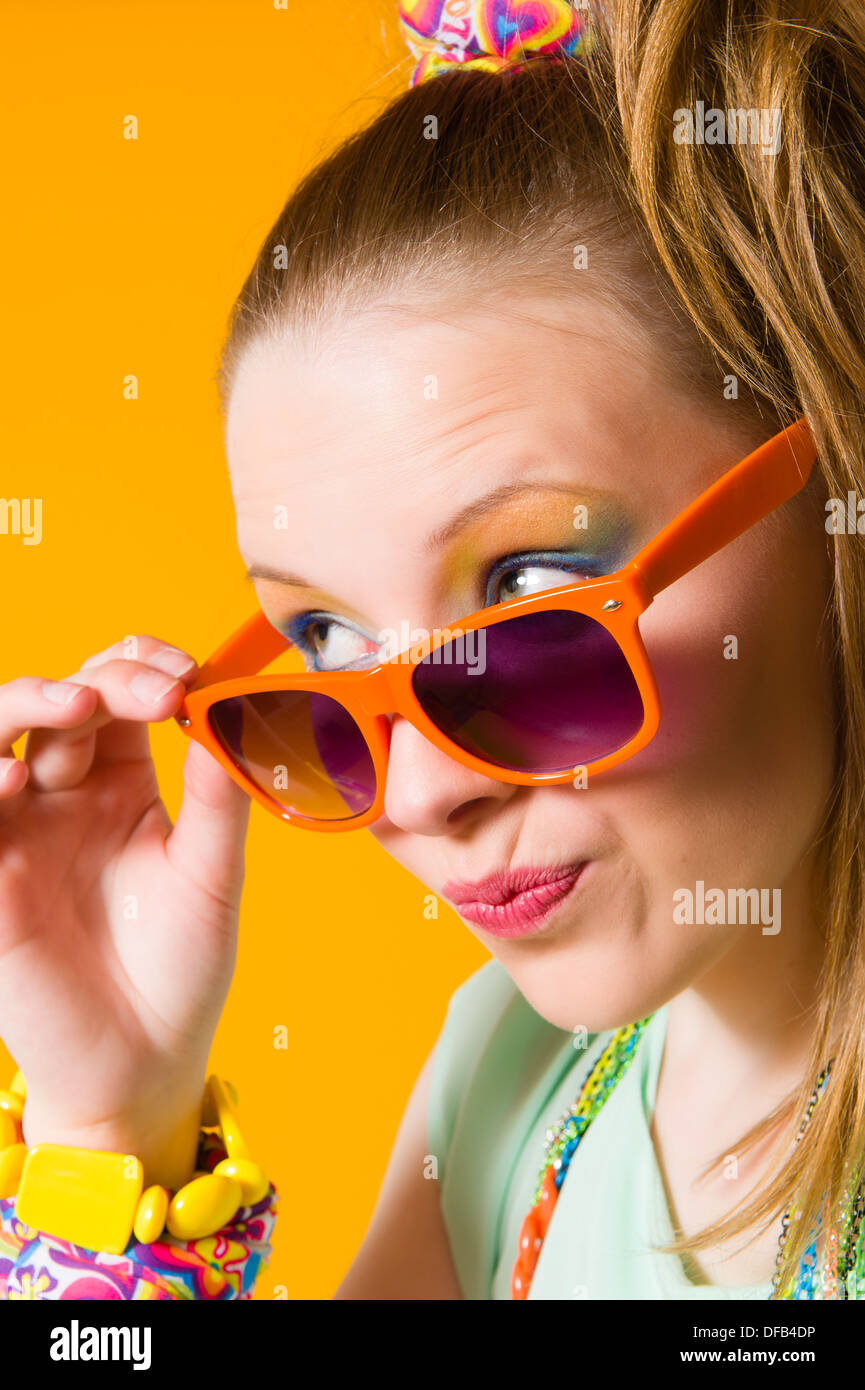 Beautiful girl wearing sunglasses, expressing faces, yellow background ...