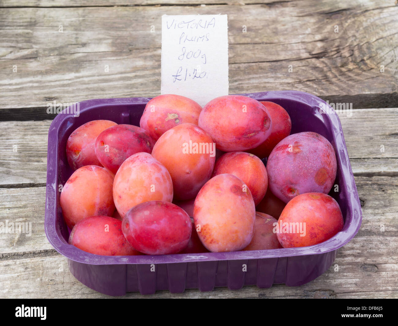 Surplus Victoria Plums for sale on a small table outside a house in a