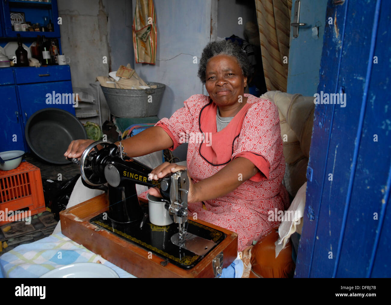 A woman works at her sewing machine in her home in Site C, Khayelitsha