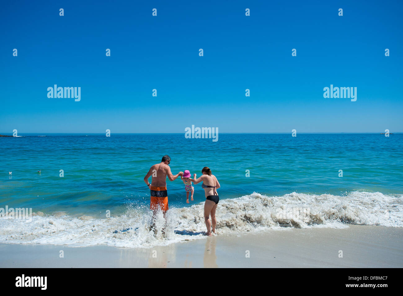Parents holding their child playfully above a wave, Camps Bay, Cape Town, South Africa Stock Photo