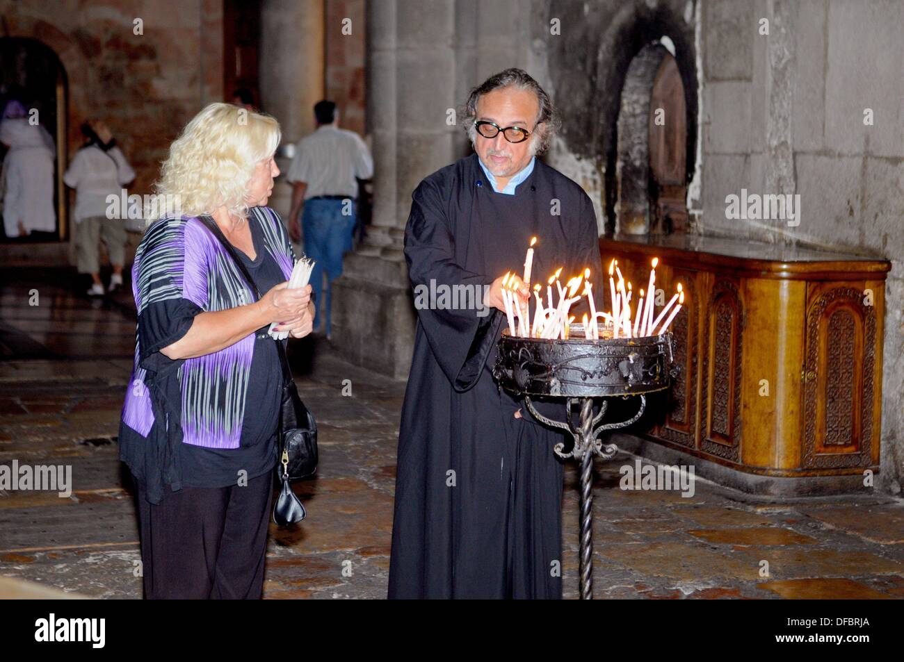 A believer talks to a priest before visiting the most important site of the Church of the Holy Sepulchre, the Aedicule (Holy Grave, Grave Chapel), the supposed location of Jesus' grave and the 14th station of the Via Dolorosa, that is visited by thousands of pilgrims and tourists daily, in Jerusalem, Israel, 10 September 2013. The Via Dolorosa (Way of Suffering) is a street in the old town of Jerusalem named after the path Jesus of Nazareth walked to his crucification. Jesus carried the cross, on which he later died via that road from the Antonia Fortress, then seat of Pilate, to Golgotha, the Stock Photo