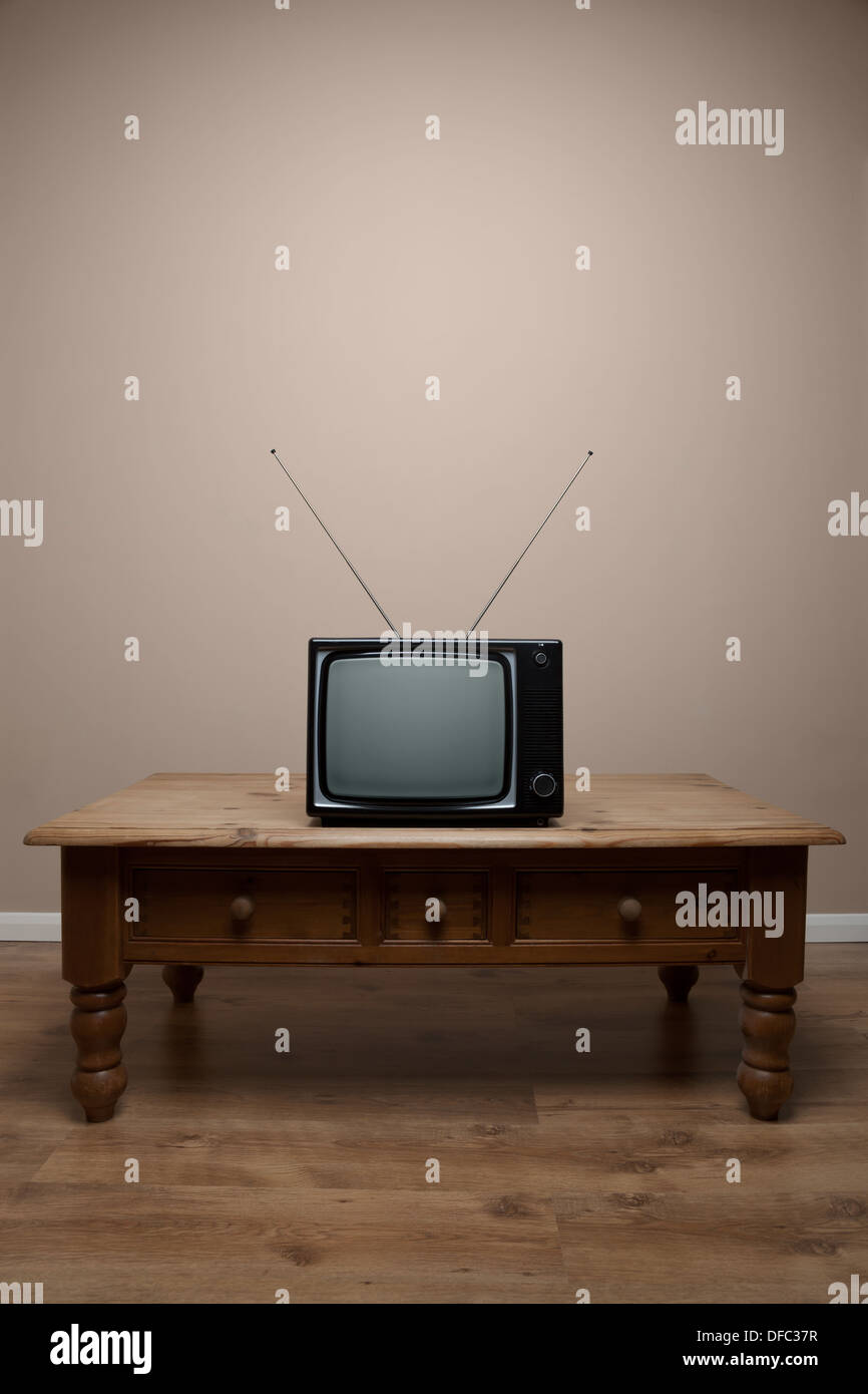 An old retro TV on a table with blank screen in an empty room Stock Photo