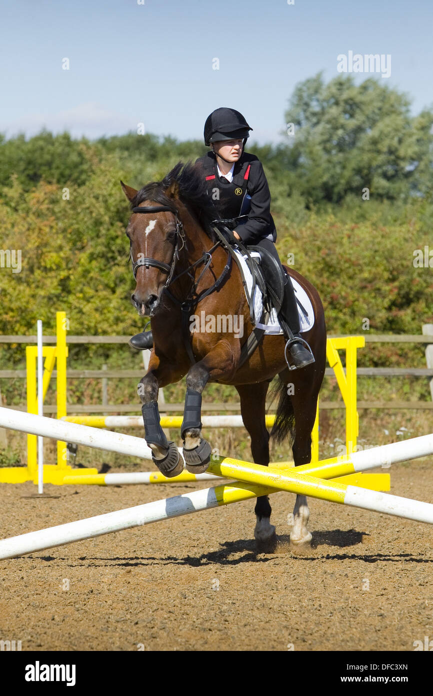 A horse and rider jumping a fence during a show jumping competition ...