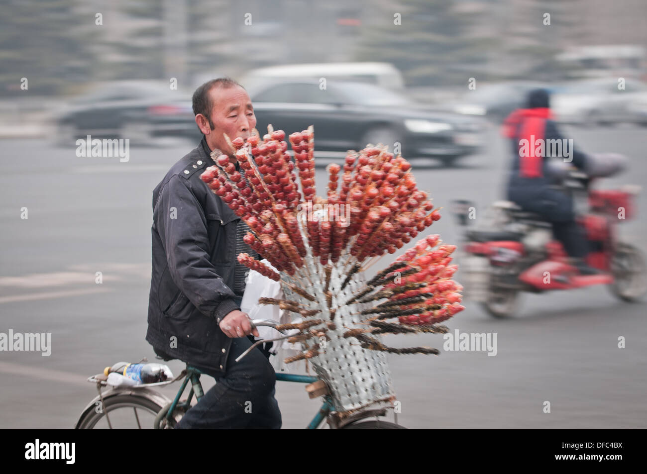 Man riding bike with Candied fruit on a stick (also called crystallized fruit or glace fruit) in Beijing, China Stock Photo