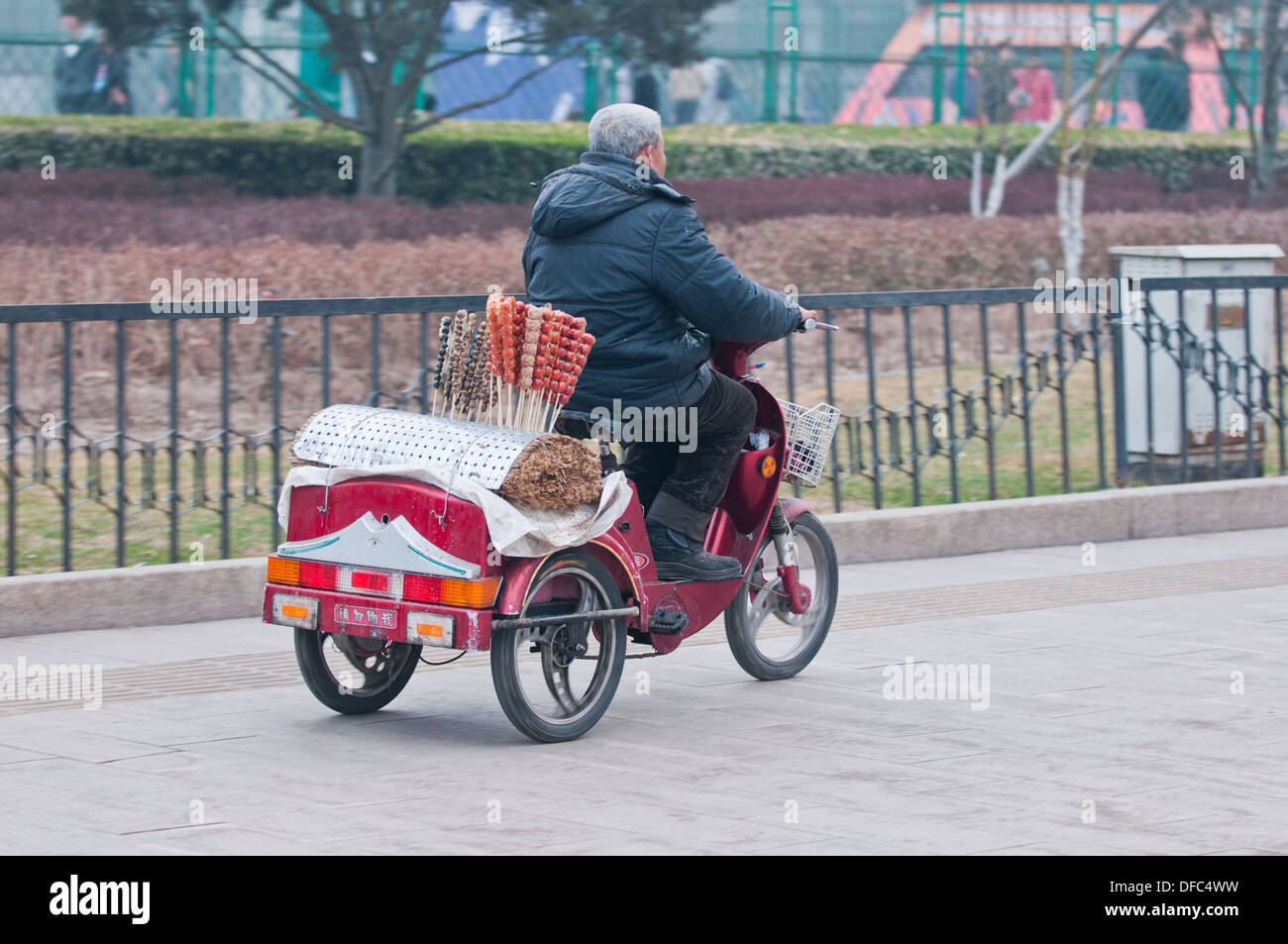 Man driving motorbike with Candied hawberries on a stick (also called crystallized fruit or glace fruit) in Beijing, China Stock Photo