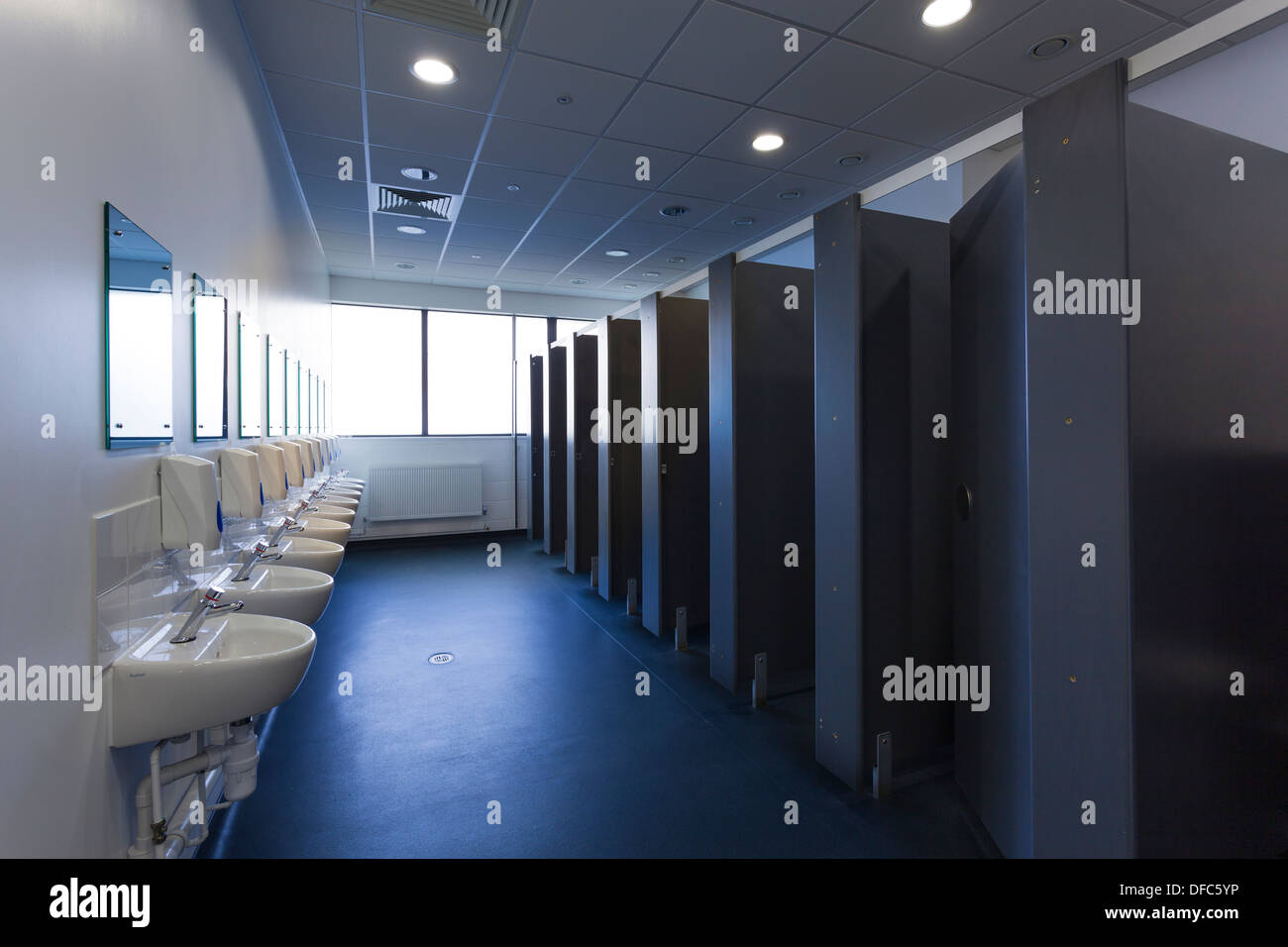 Unoccupied female public toilets with wash basins and cubicles. Stock Photo