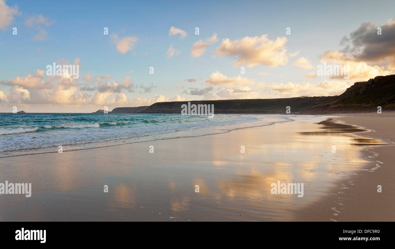 Start of a summers day on Sennen beach in Whitesand Bay near Lands End Cornwall, clouds reflected in the wet sand at low tide. Stock Photo